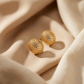 Gold earrings on beige fabric
