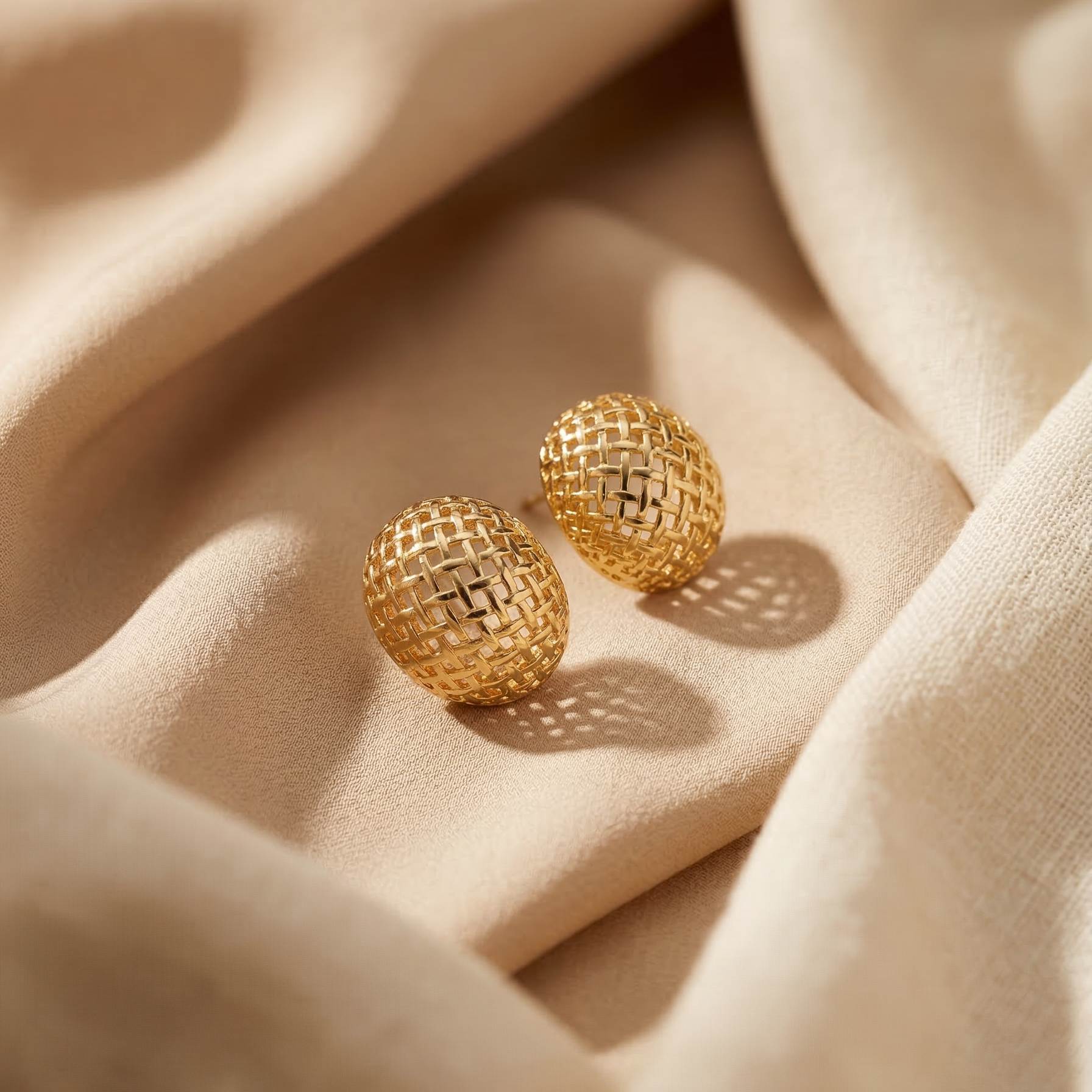 Gold earrings on beige fabric
