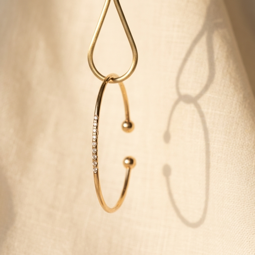 Gold earrings on a textured beige surface