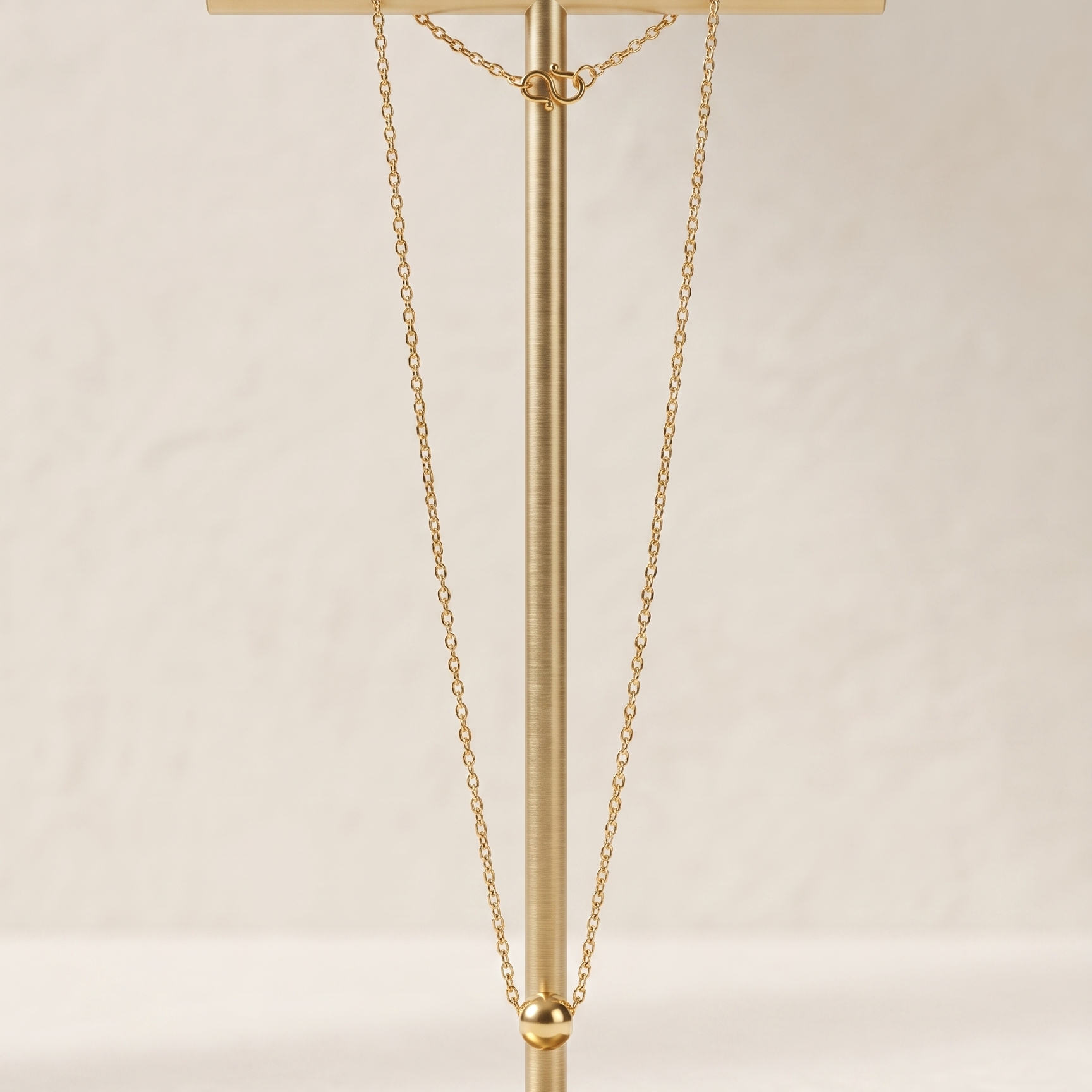 Gold necklace on a matching gold stand against a light background