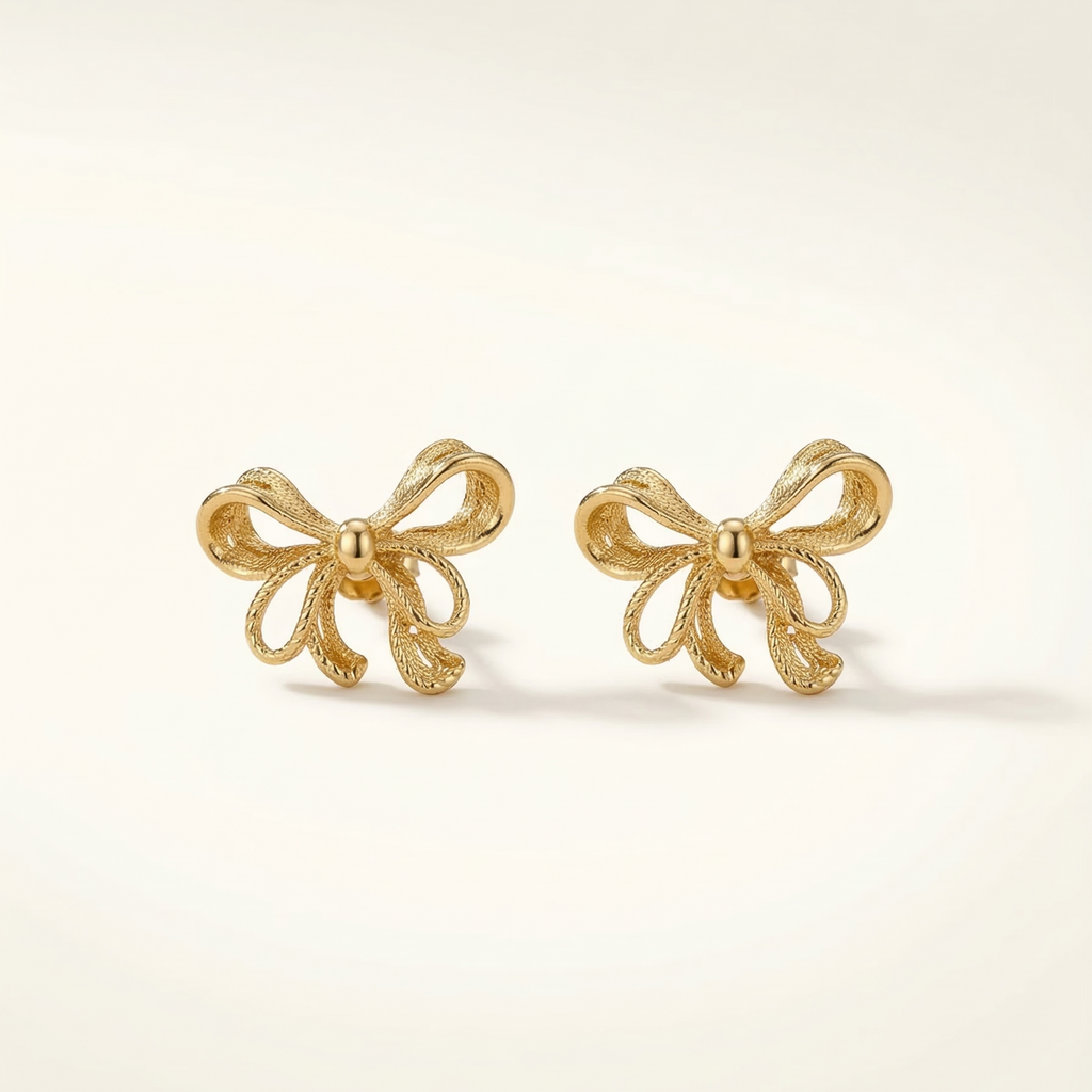Gold bow-shaped earrings on a light beige background