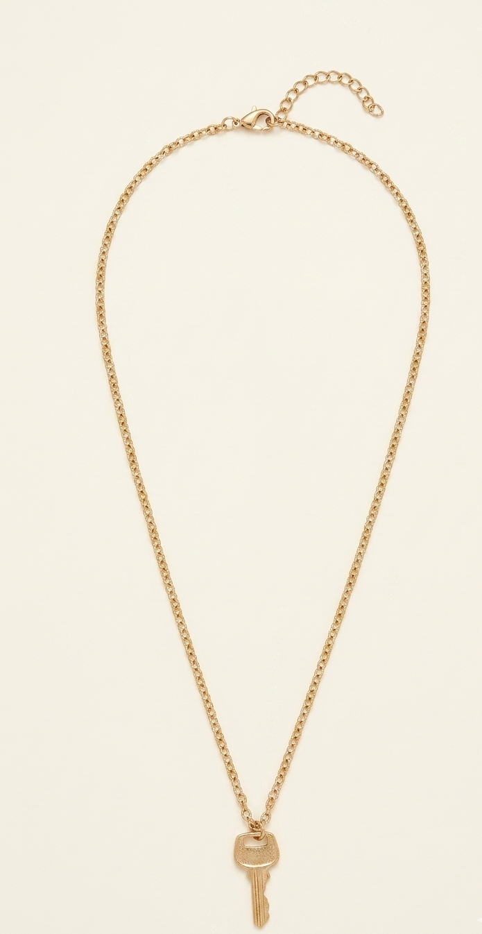 Gold necklace with a key pendant on a beige background