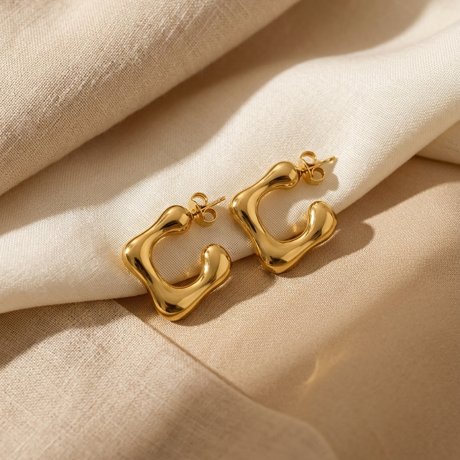 Gold earrings on beige fabric