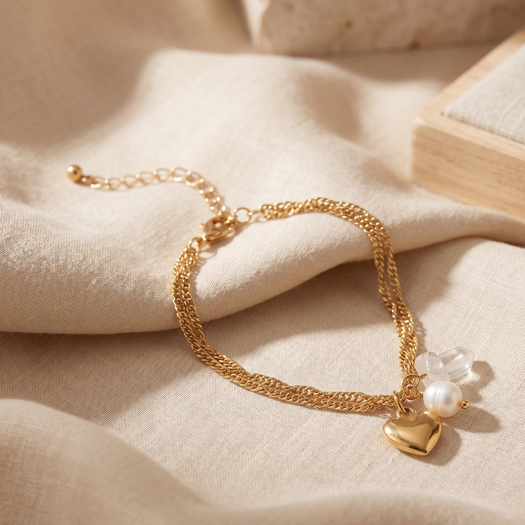 Gold bracelet with heart charm and pearl on beige fabric
