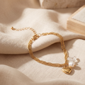 Gold bracelet with heart charm and pearl on beige fabric