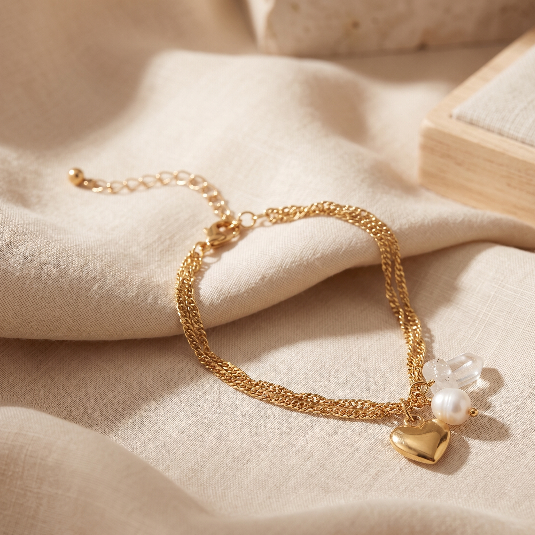 Gold bracelet with heart charm and pearl on beige fabric