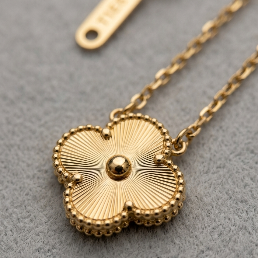 Gold necklace with a detailed pendant on a gray background