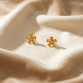 Pair of gold flower-shaped earrings on beige fabric