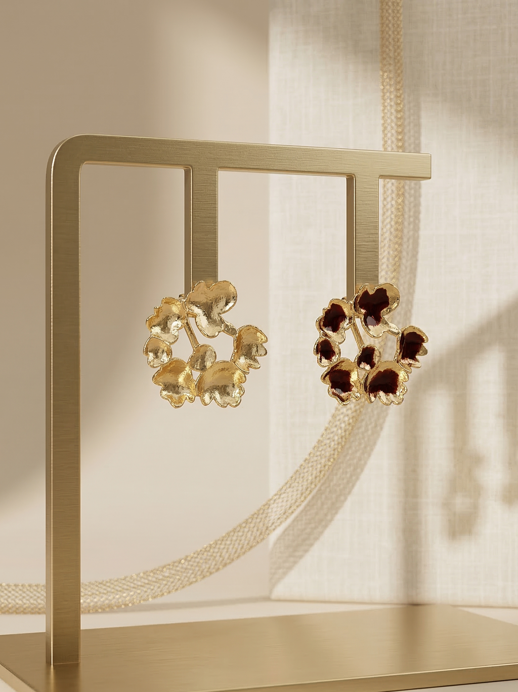 Gold earrings with brown gemstones on a gold stand against a neutral background