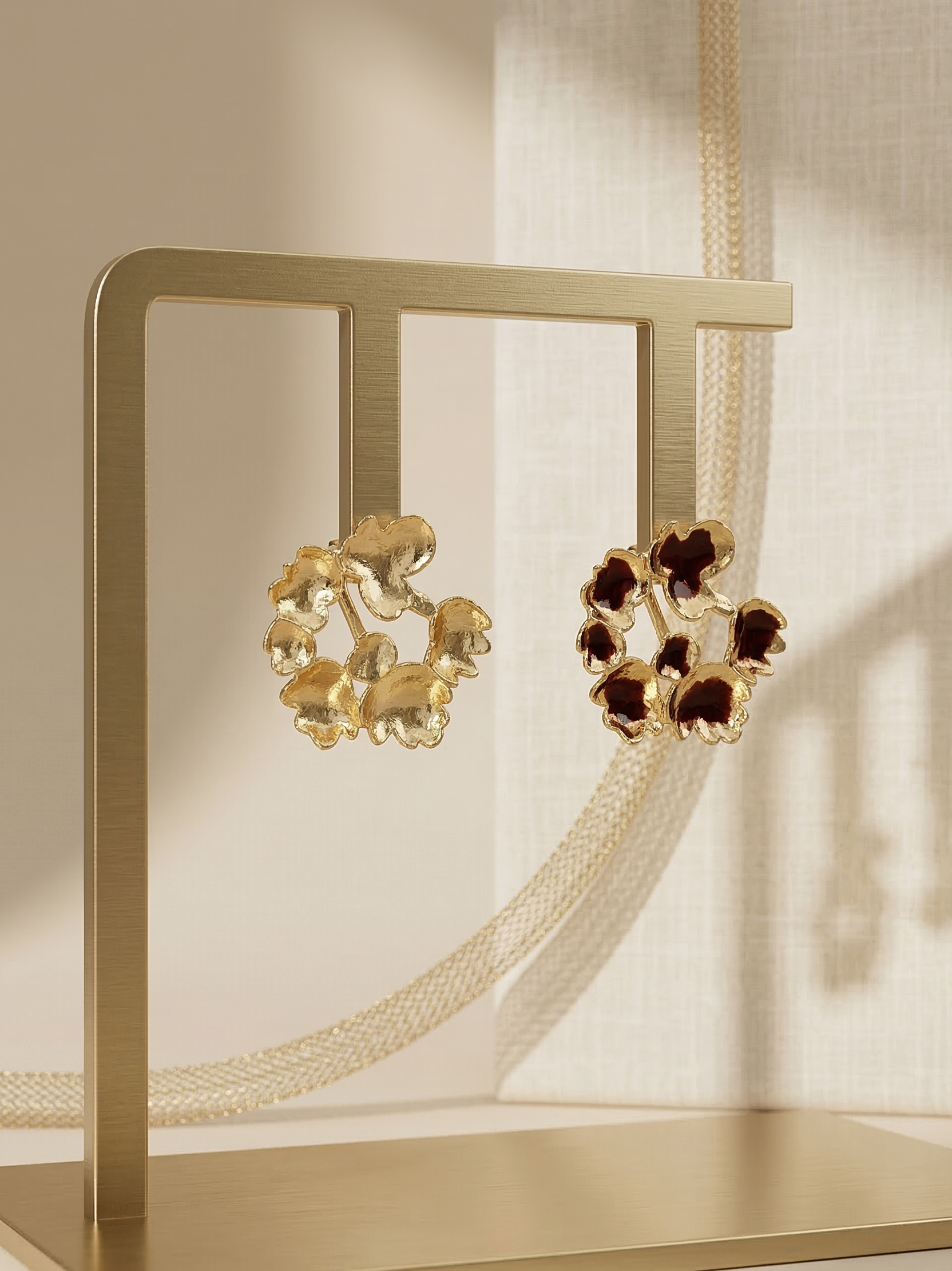 Gold earrings with brown gemstones on a gold stand against a neutral background