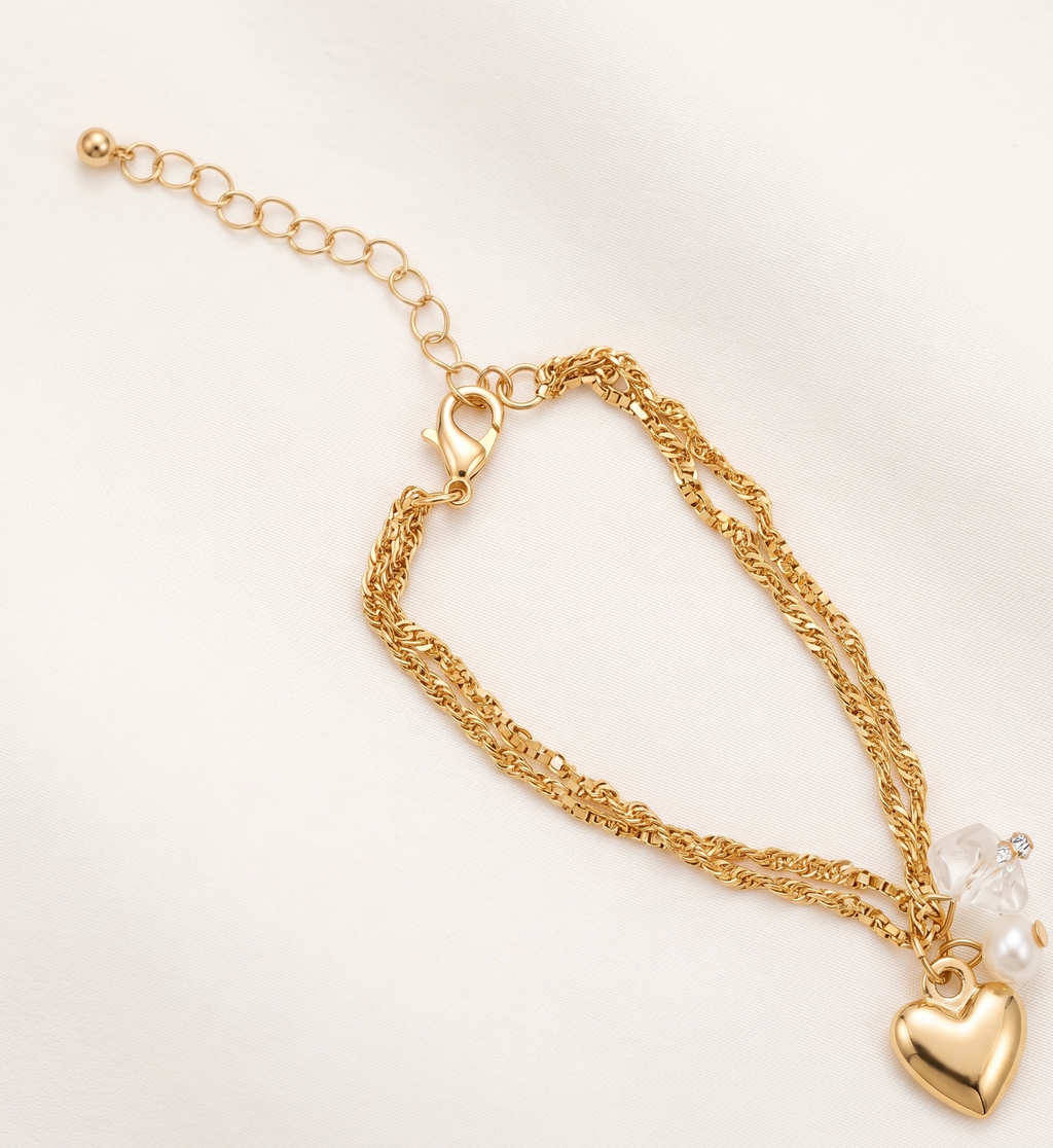 Gold bracelet with heart charm and pearl on a white background