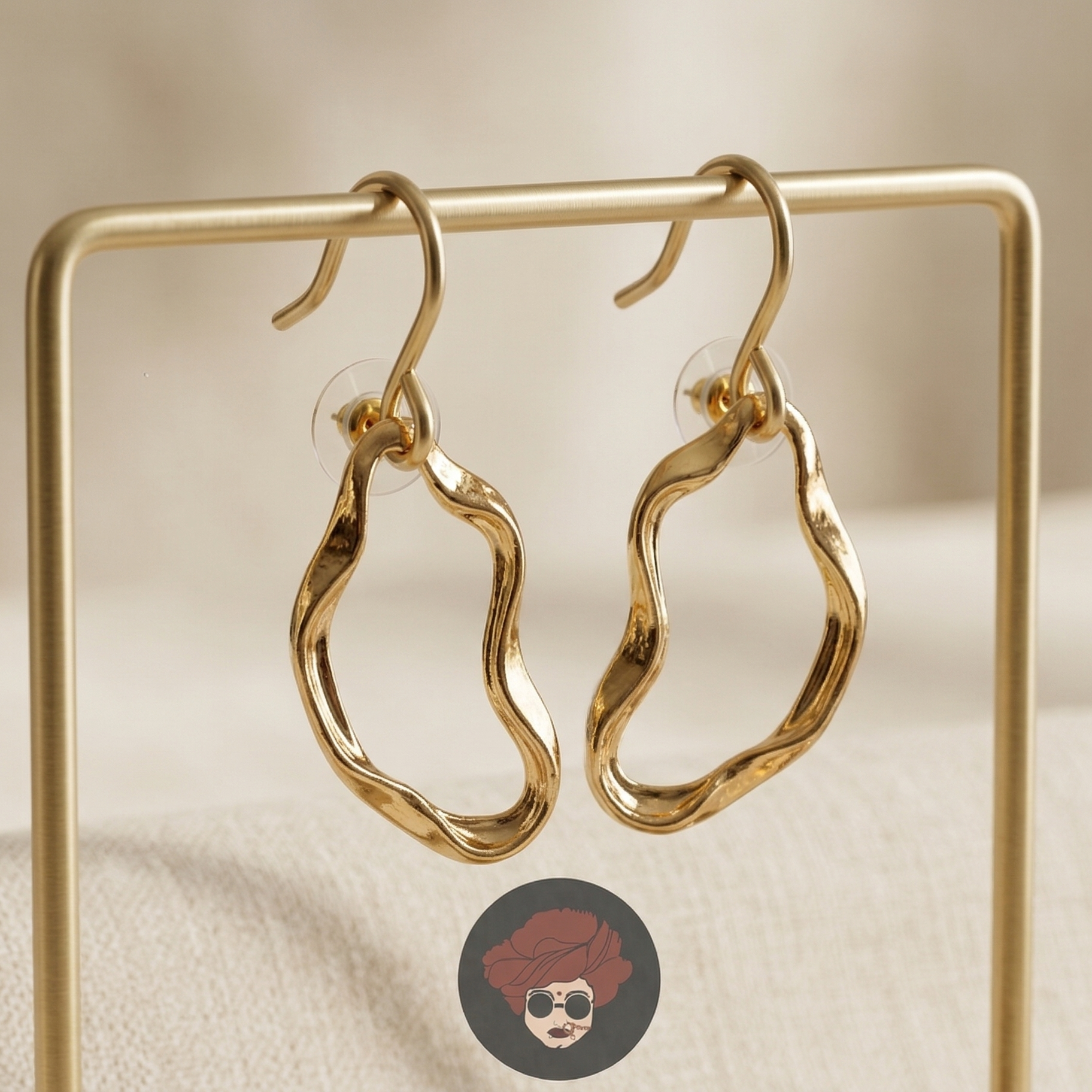 Gold hoop earrings on a gold stand with a blurred background