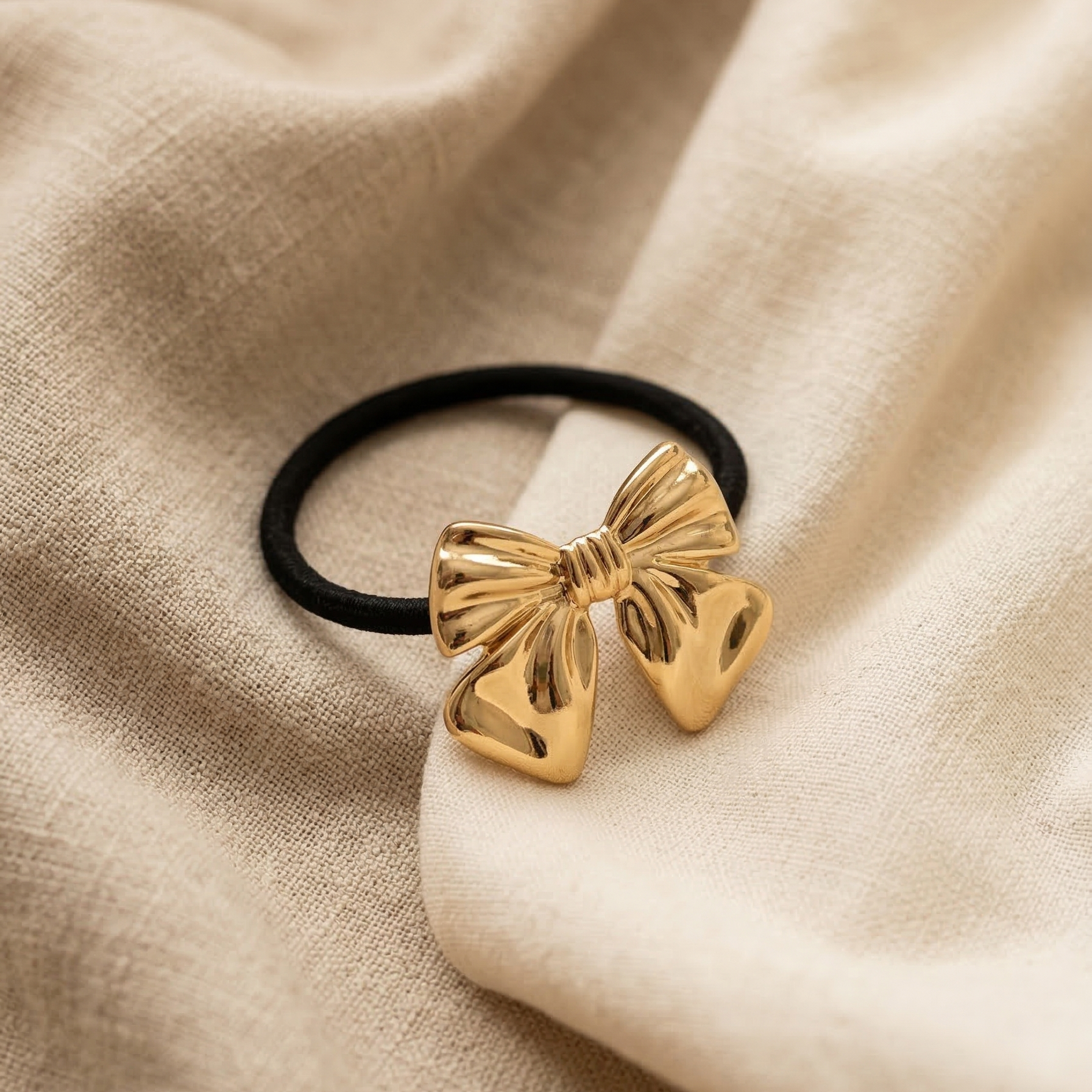 Gold bow hair tie on beige fabric