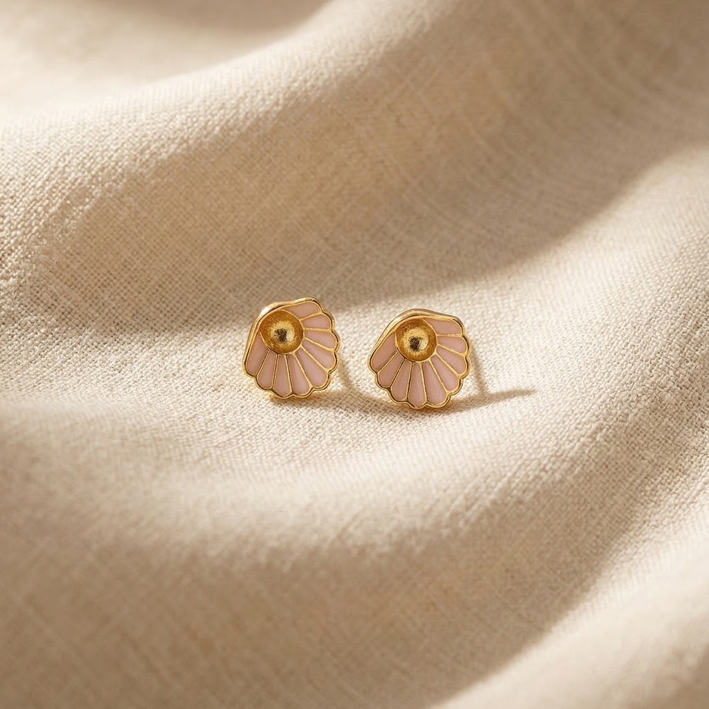 Pair of gold and pink floral earrings on a beige fabric background