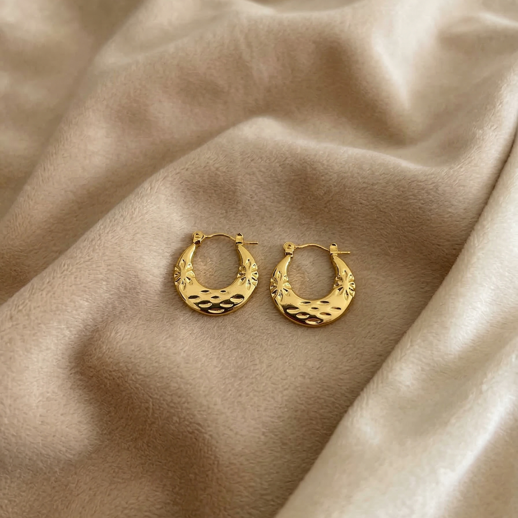 Gold hoop earrings on a beige fabric background