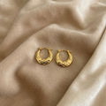Gold hoop earrings on a beige fabric background