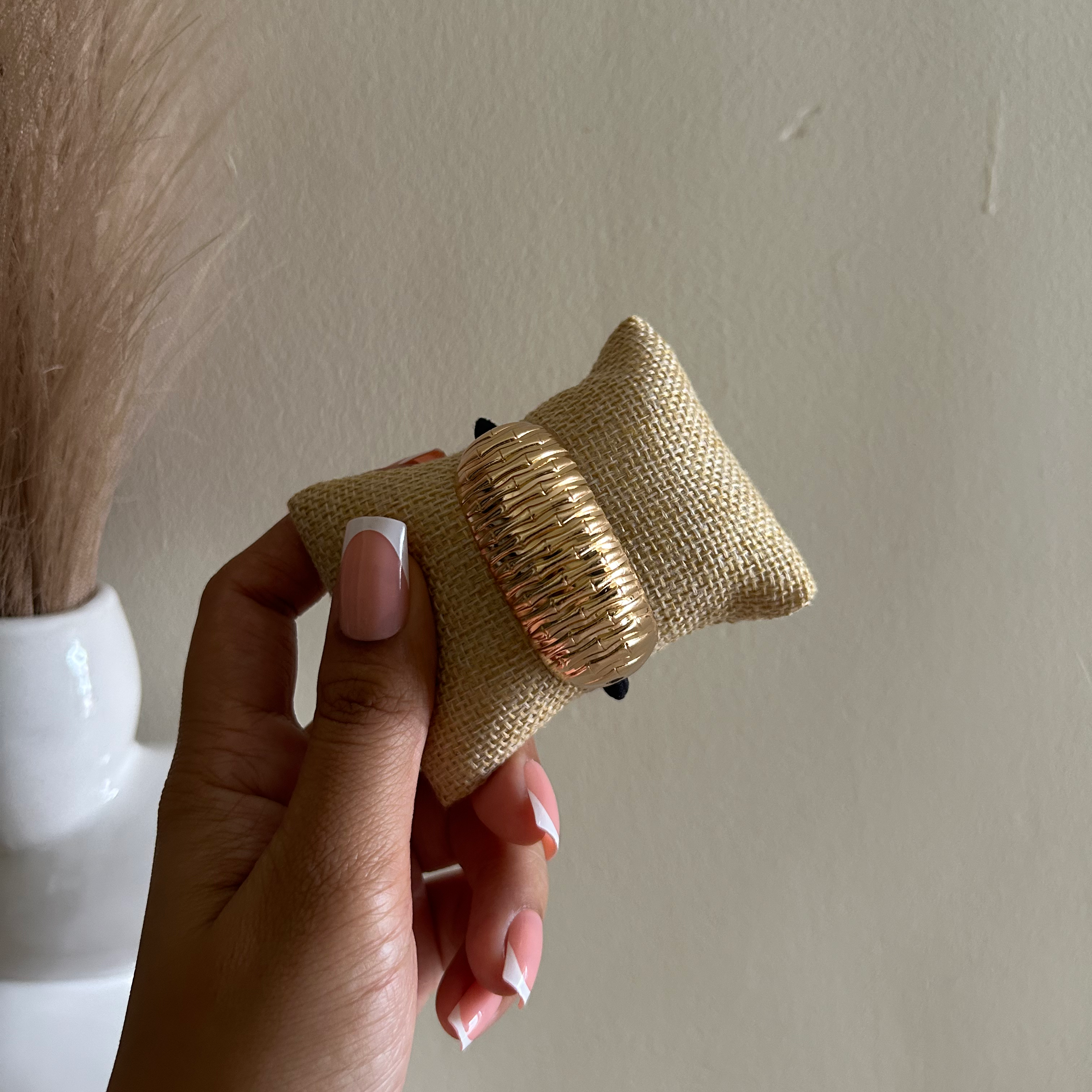Hand holding a small woven object against a plain background