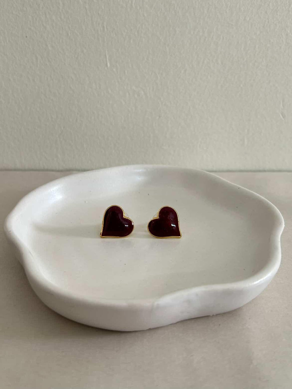 Heart-shaped earrings on a white dish with a plain background
