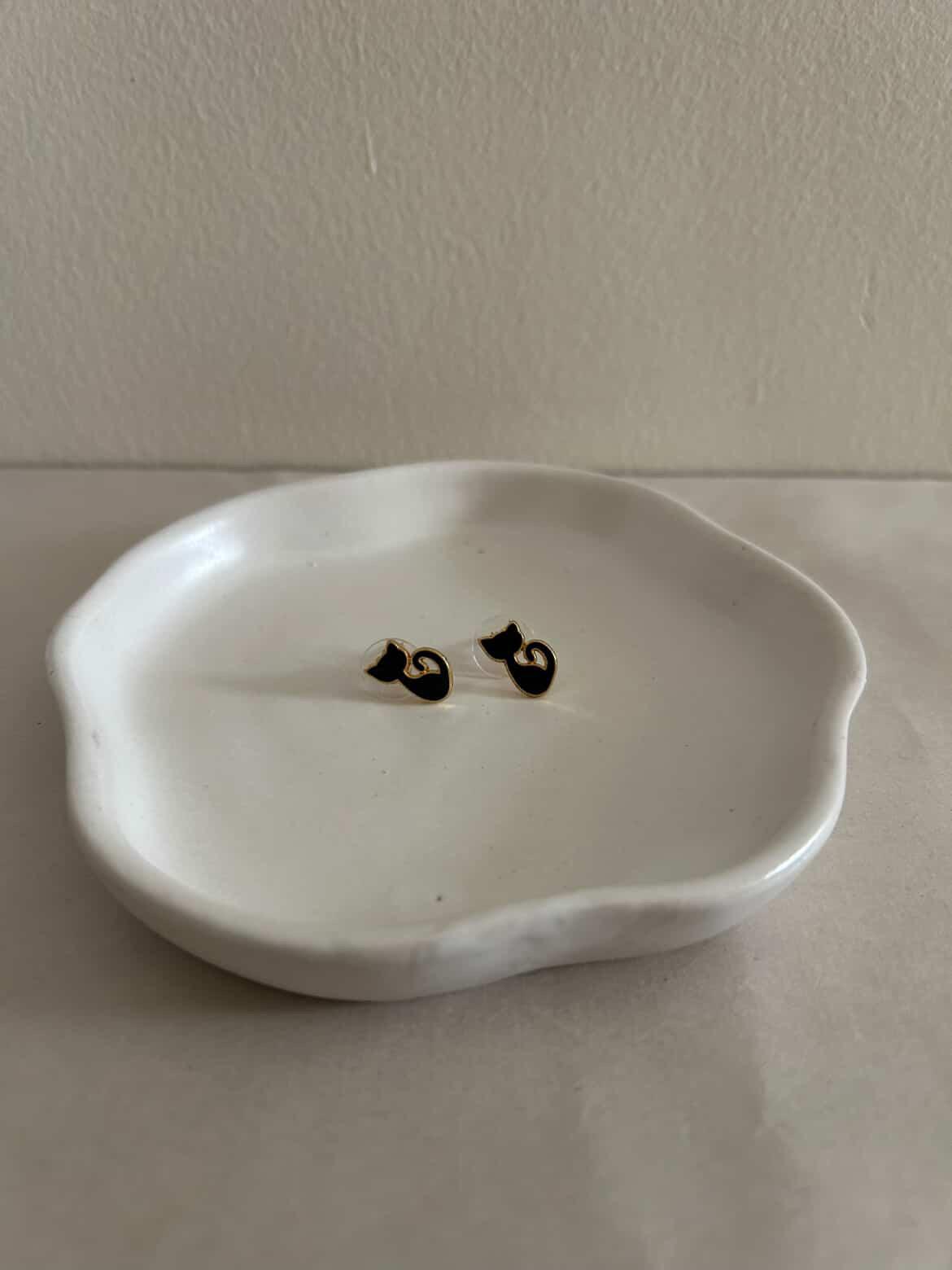 White ceramic dish with black cat-shaped decorations on a white surface.