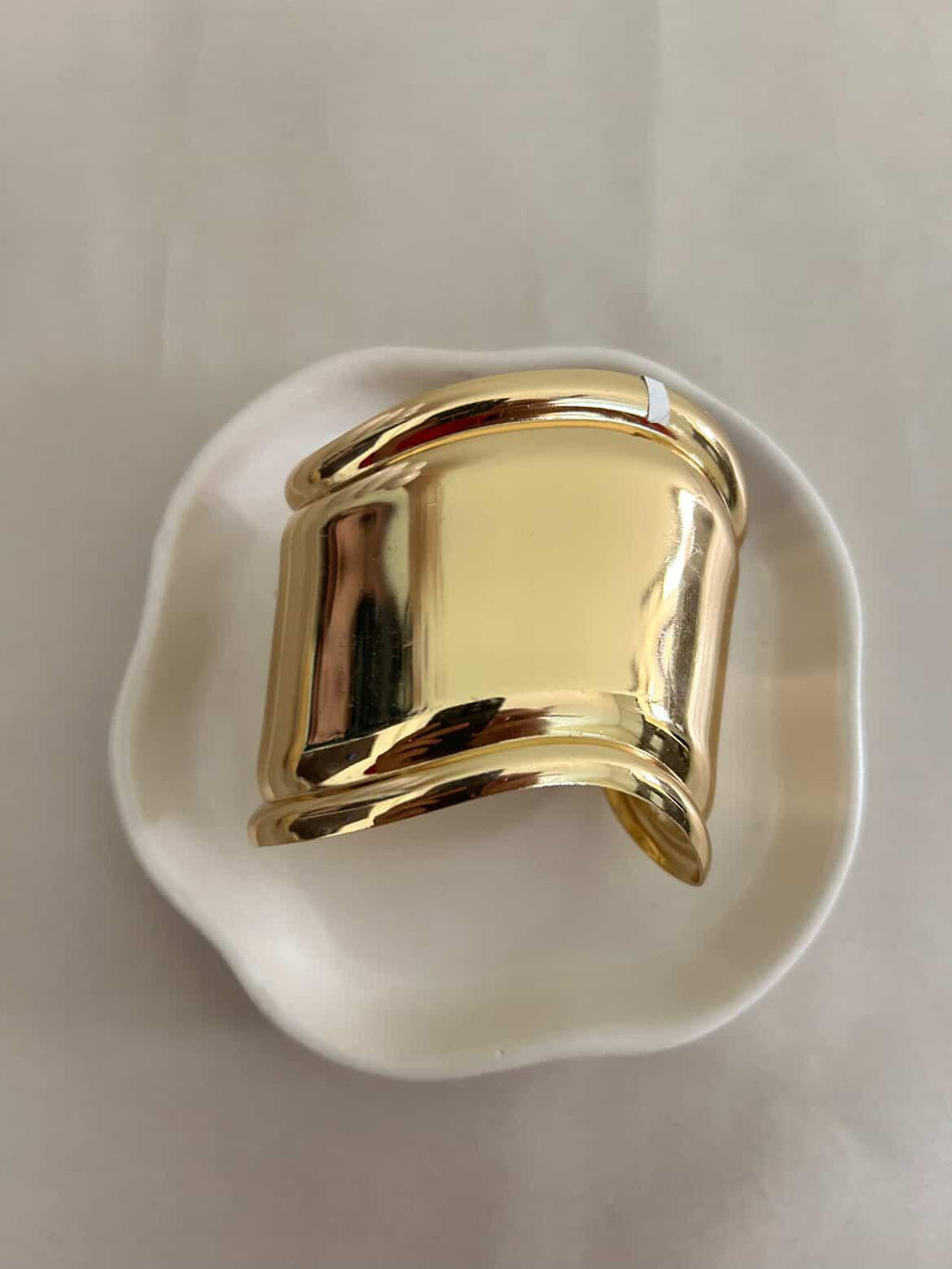 Gold ring on a white dish with a plain background