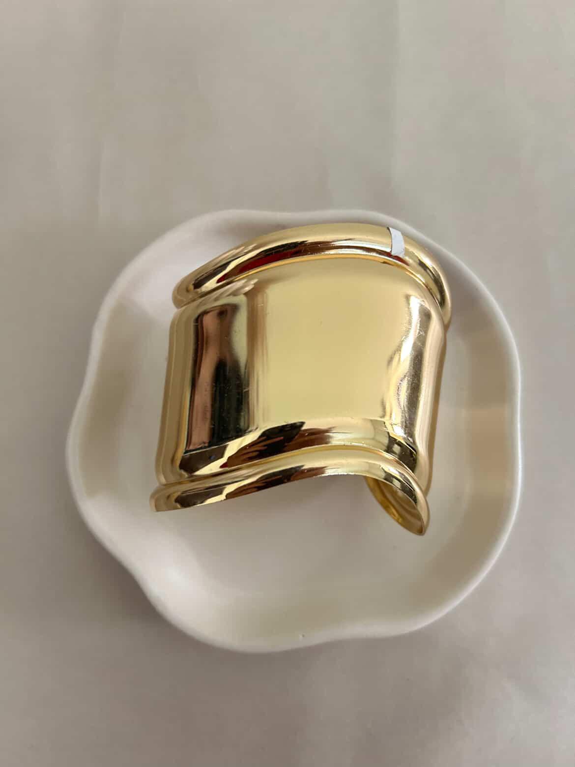 Gold ring on a white dish with a plain background