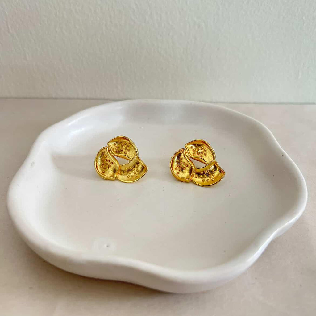Gold earrings on a white dish with a plain background